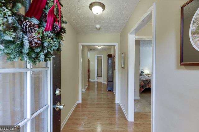 hallway featuring light wood-type flooring and a textured ceiling