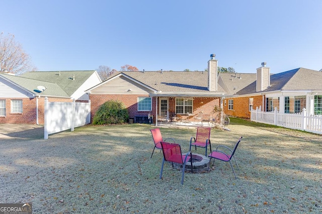 back of property with a lawn and an outdoor fire pit