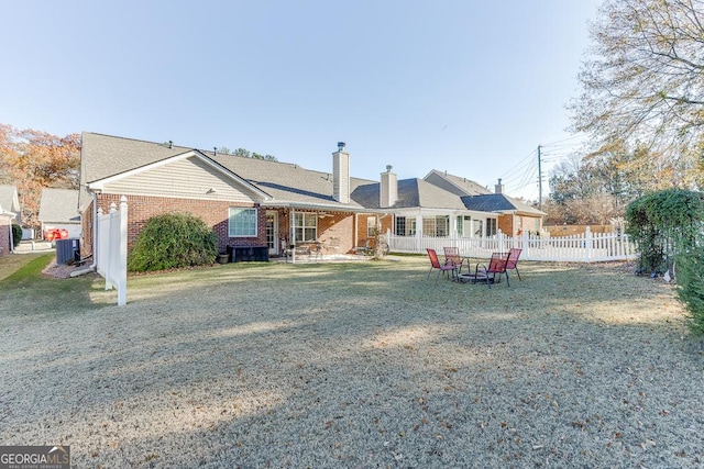 rear view of house featuring cooling unit and a yard