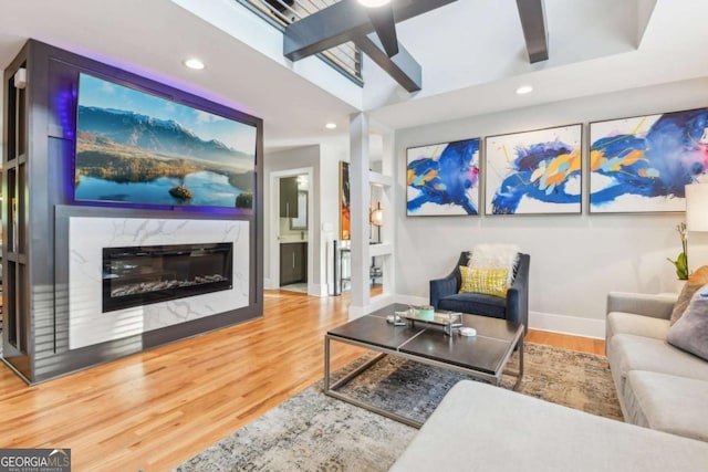 living room featuring a premium fireplace, ceiling fan, wood-type flooring, and vaulted ceiling