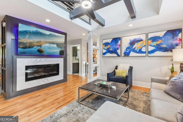 living room featuring a high end fireplace, wood-type flooring, and beam ceiling