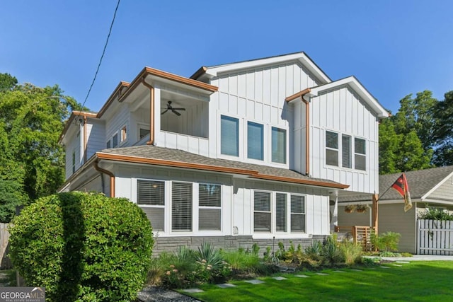 back of property featuring ceiling fan and a yard