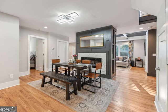 dining room featuring a high end fireplace and light hardwood / wood-style flooring