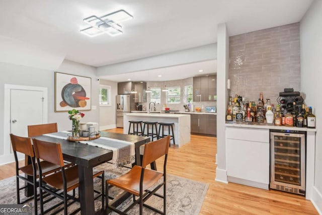 dining space with bar, light hardwood / wood-style floors, and beverage cooler