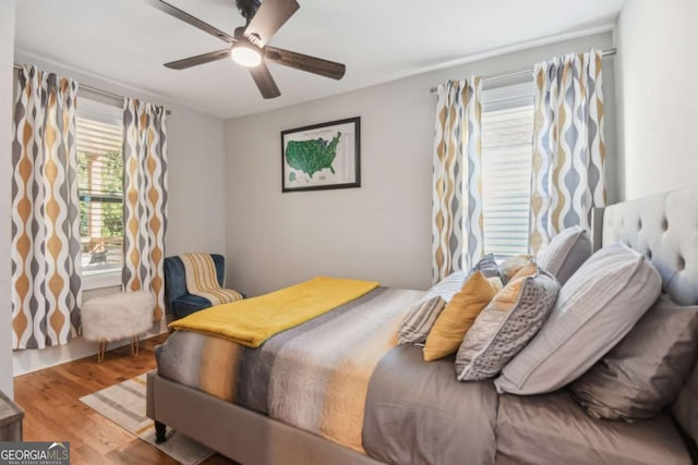 bedroom with multiple windows, ceiling fan, and hardwood / wood-style flooring