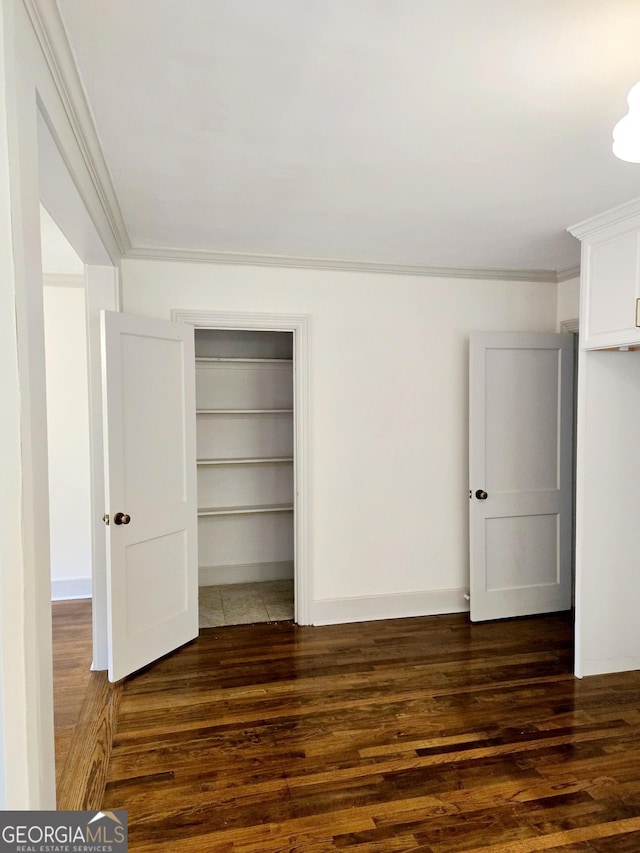 unfurnished bedroom with dark hardwood / wood-style floors, crown molding, and a closet