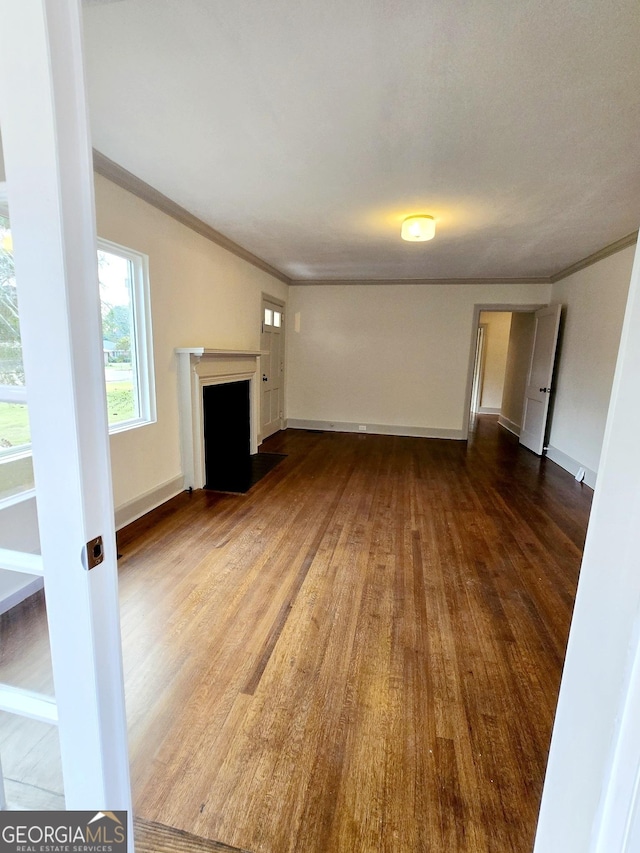 unfurnished living room featuring hardwood / wood-style flooring and ornamental molding