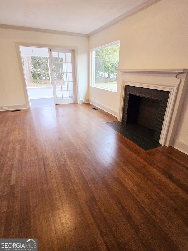 unfurnished living room with dark hardwood / wood-style flooring, crown molding, and a brick fireplace