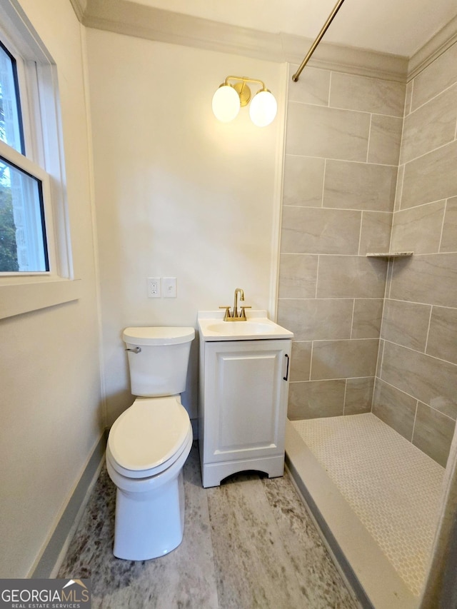 bathroom with vanity, toilet, and tiled shower