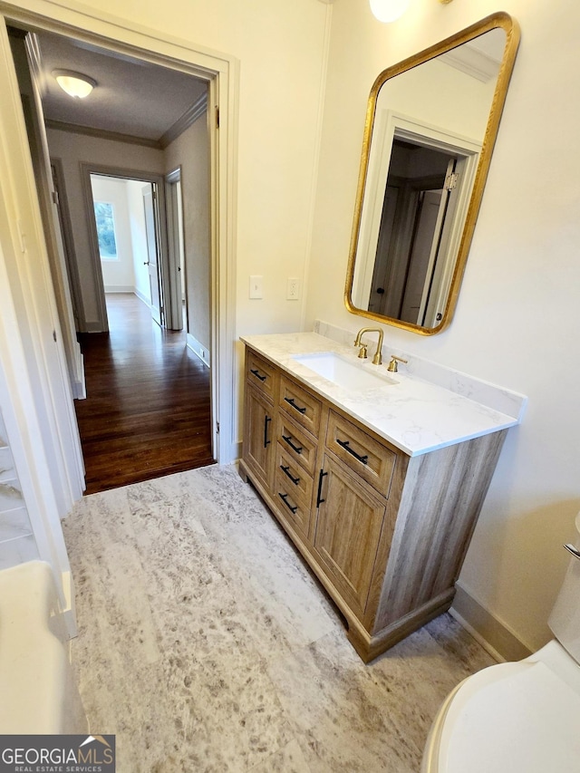 bathroom featuring vanity, toilet, wood-type flooring, and ornamental molding