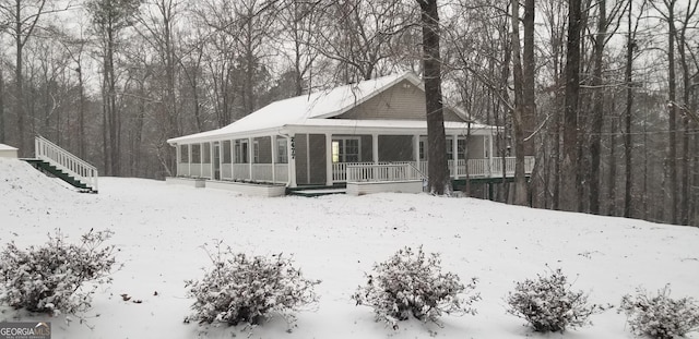 snow covered back of property with covered porch