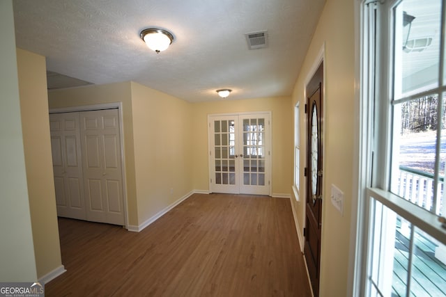 hall featuring hardwood / wood-style floors, plenty of natural light, french doors, and a textured ceiling