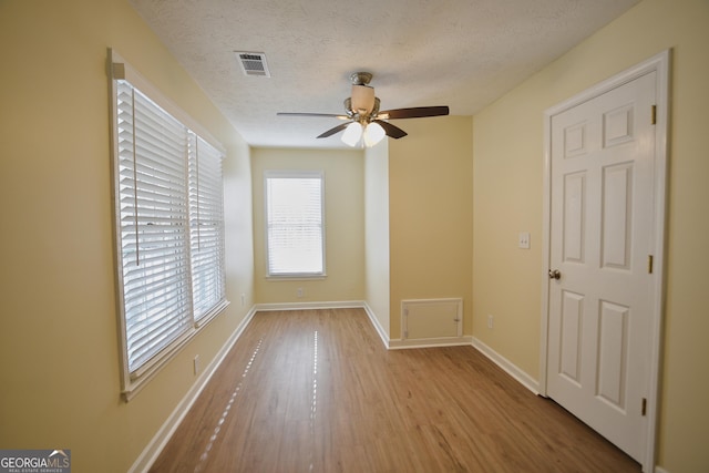 empty room featuring baseboards, a textured ceiling, visible vents, a ceiling fan, and wood finished floors