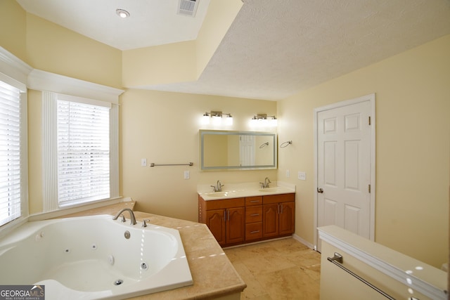 bathroom featuring a whirlpool tub, visible vents, double vanity, and a sink