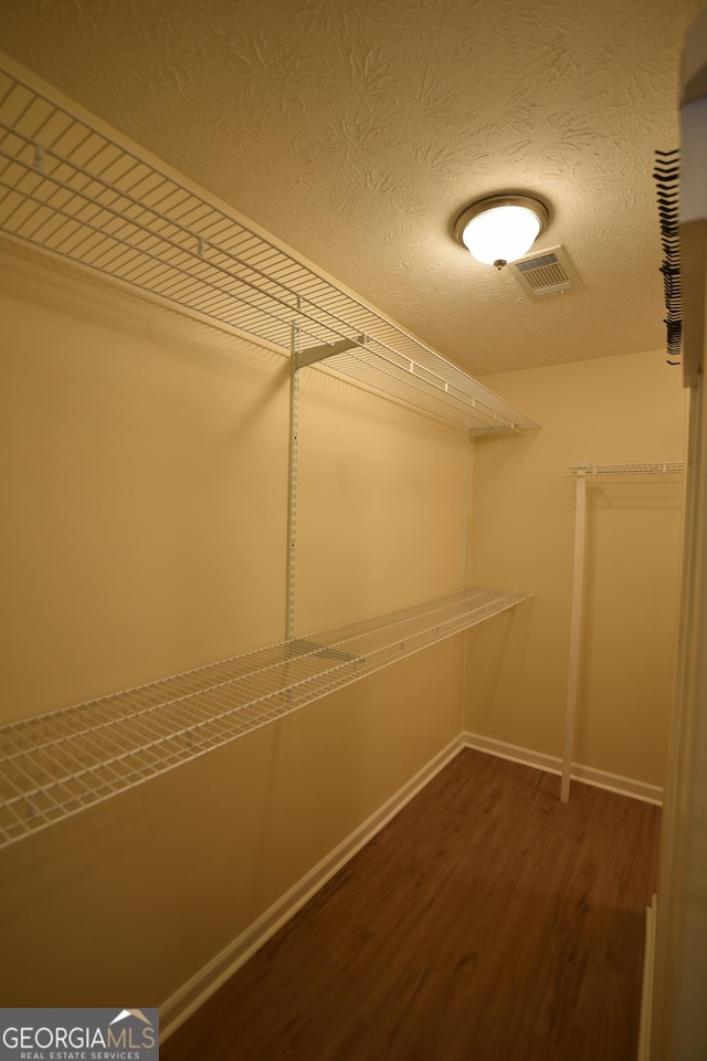 walk in closet with dark wood-type flooring