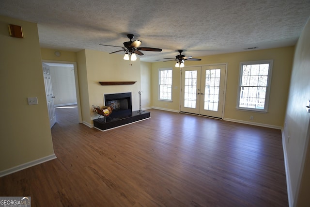 unfurnished living room featuring plenty of natural light, a textured ceiling, and dark hardwood / wood-style flooring