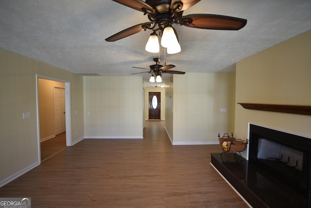 unfurnished living room with ceiling fan, a textured ceiling, and dark hardwood / wood-style flooring