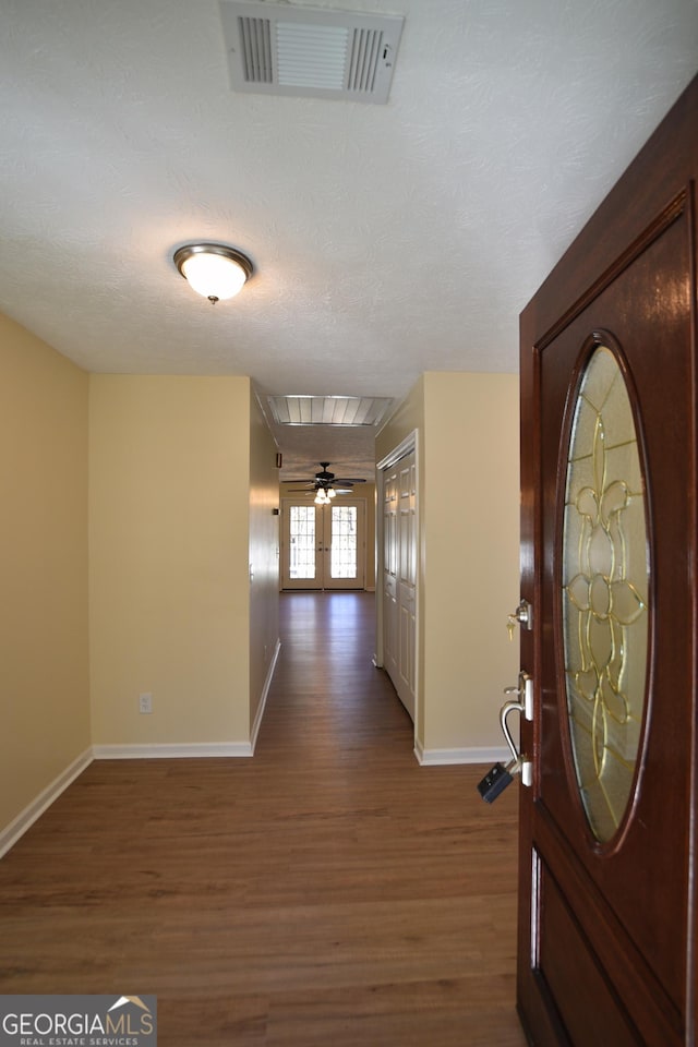 entryway with baseboards, visible vents, dark wood-type flooring, and a textured ceiling