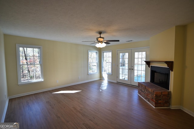 unfurnished living room featuring a wealth of natural light, a ceiling fan, a textured ceiling, and dark wood-style flooring