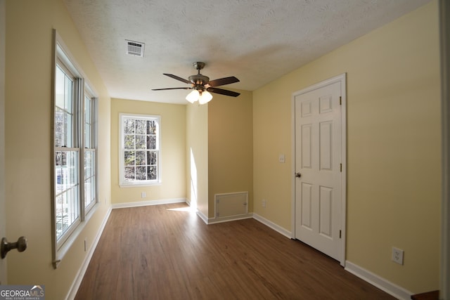 spare room featuring a textured ceiling, visible vents, ceiling fan, and dark wood-style flooring