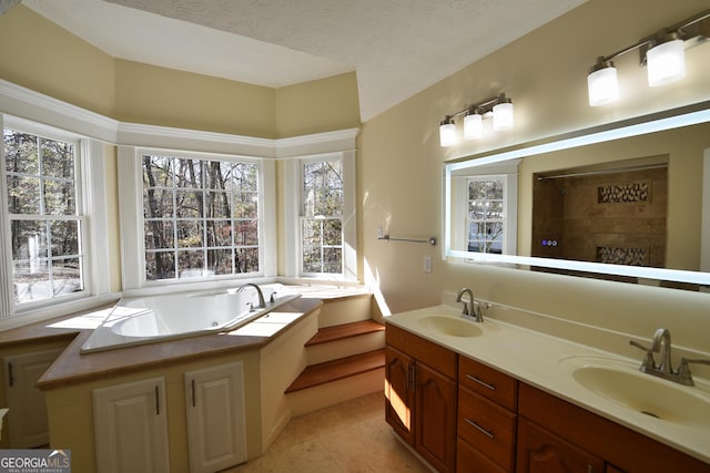 full bathroom featuring a tub with jets, tile patterned flooring, a sink, and a textured ceiling