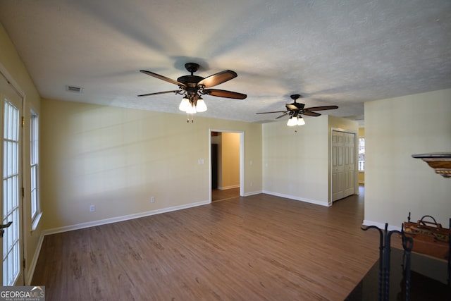 unfurnished living room with wood finished floors, a textured ceiling, ceiling fan, and visible vents