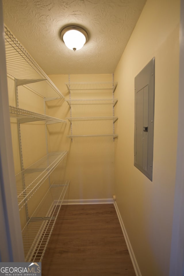 walk in closet with electric panel and wood finished floors