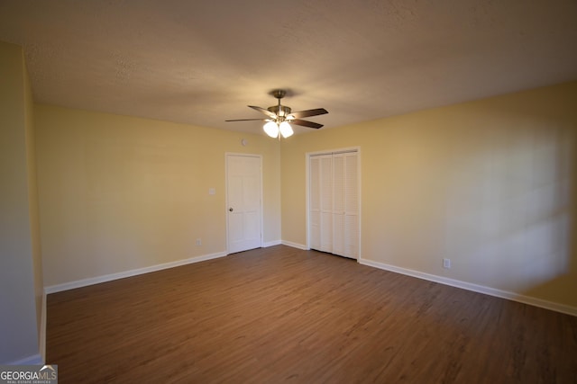 spare room with dark wood-style floors, a textured ceiling, baseboards, and a ceiling fan