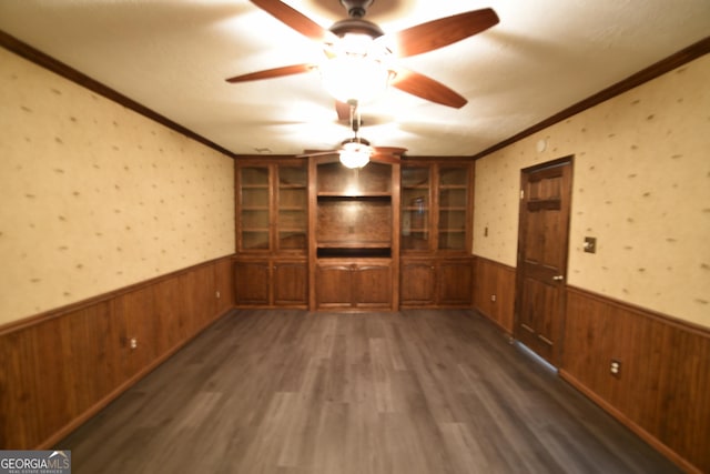 empty room with a wainscoted wall, crown molding, ceiling fan, and wallpapered walls