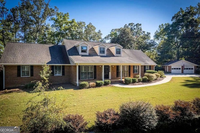 cape cod-style house featuring covered porch, a garage, an outdoor structure, and a front lawn