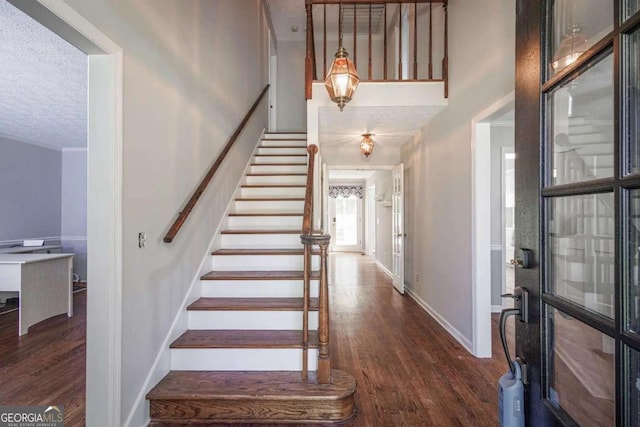 foyer entrance with dark hardwood / wood-style floors and a textured ceiling