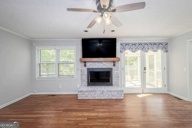 unfurnished living room with a textured ceiling, hardwood / wood-style flooring, a brick fireplace, and ornamental molding