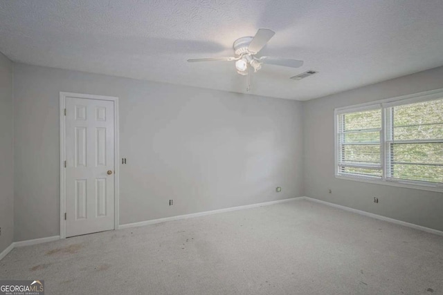 carpeted spare room featuring a textured ceiling and ceiling fan