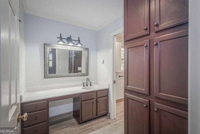 bathroom with hardwood / wood-style flooring, vanity, and crown molding