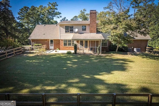 rear view of property featuring a yard and a sunroom