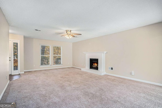 unfurnished living room with a textured ceiling, ceiling fan, and light carpet