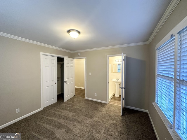 unfurnished bedroom featuring ensuite bath, crown molding, sink, dark colored carpet, and a closet