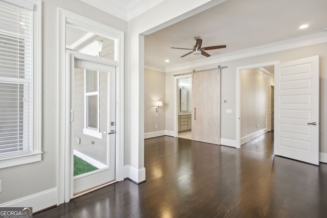 spare room with dark hardwood / wood-style flooring, a barn door, ceiling fan, and ornamental molding