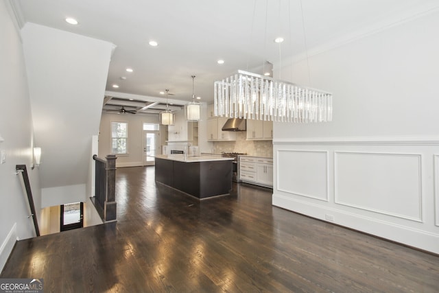 kitchen featuring exhaust hood, hanging light fixtures, stainless steel stove, an island with sink, and dark hardwood / wood-style flooring