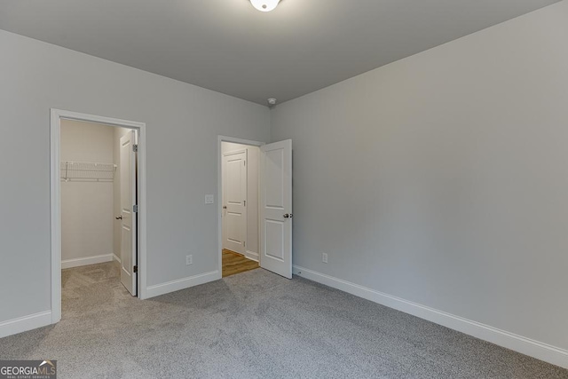 unfurnished bedroom featuring light carpet, a walk in closet, and a closet