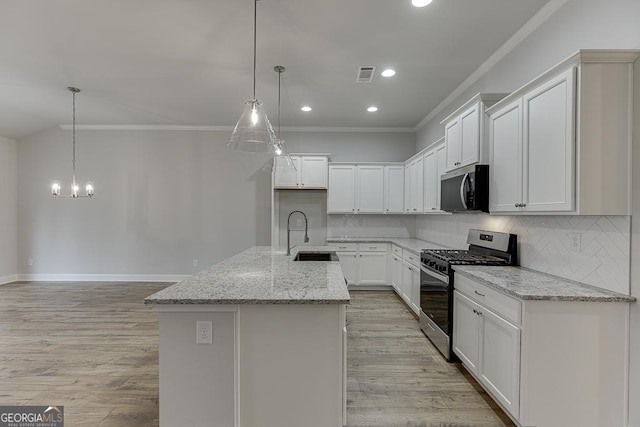 kitchen with sink, white cabinetry, hanging light fixtures, stainless steel appliances, and an island with sink