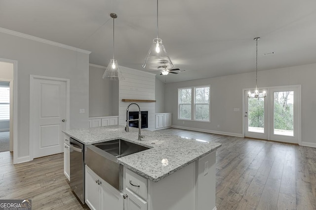 kitchen with decorative light fixtures, dishwasher, an island with sink, and white cabinets