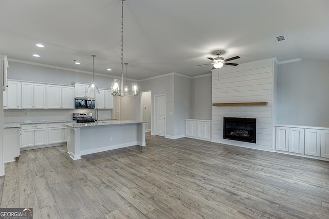 kitchen featuring white cabinetry, an island with sink, pendant lighting, stainless steel appliances, and light hardwood / wood-style floors