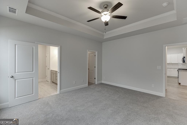 unfurnished bedroom featuring light colored carpet, ornamental molding, and a tray ceiling