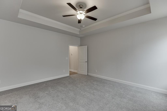 spare room featuring ceiling fan, ornamental molding, a tray ceiling, and carpet floors