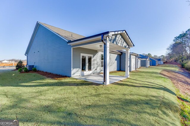 rear view of house with french doors, central AC, a patio, and a lawn