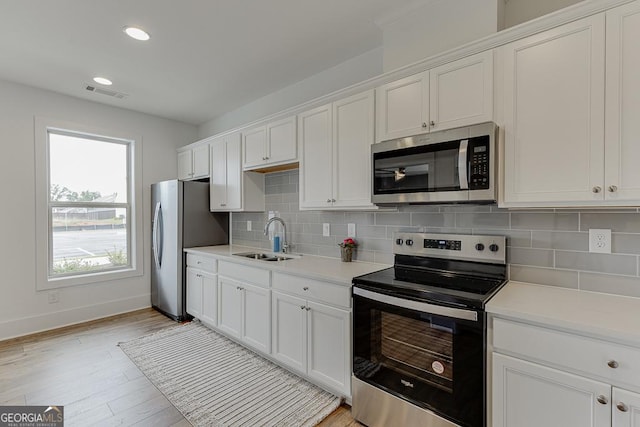 kitchen with backsplash, stainless steel appliances, sink, and white cabinets