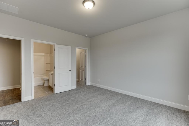 unfurnished bedroom with connected bathroom and light carpet