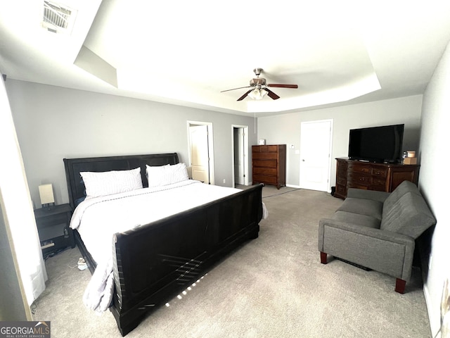 bedroom featuring a raised ceiling, ceiling fan, and light carpet