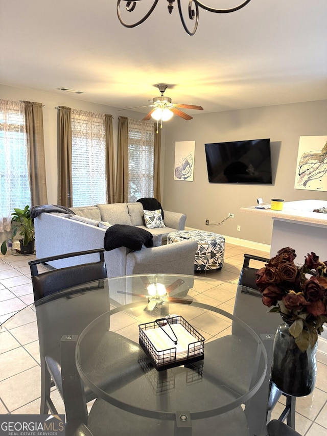 living room with a wealth of natural light, light tile patterned floors, and ceiling fan with notable chandelier